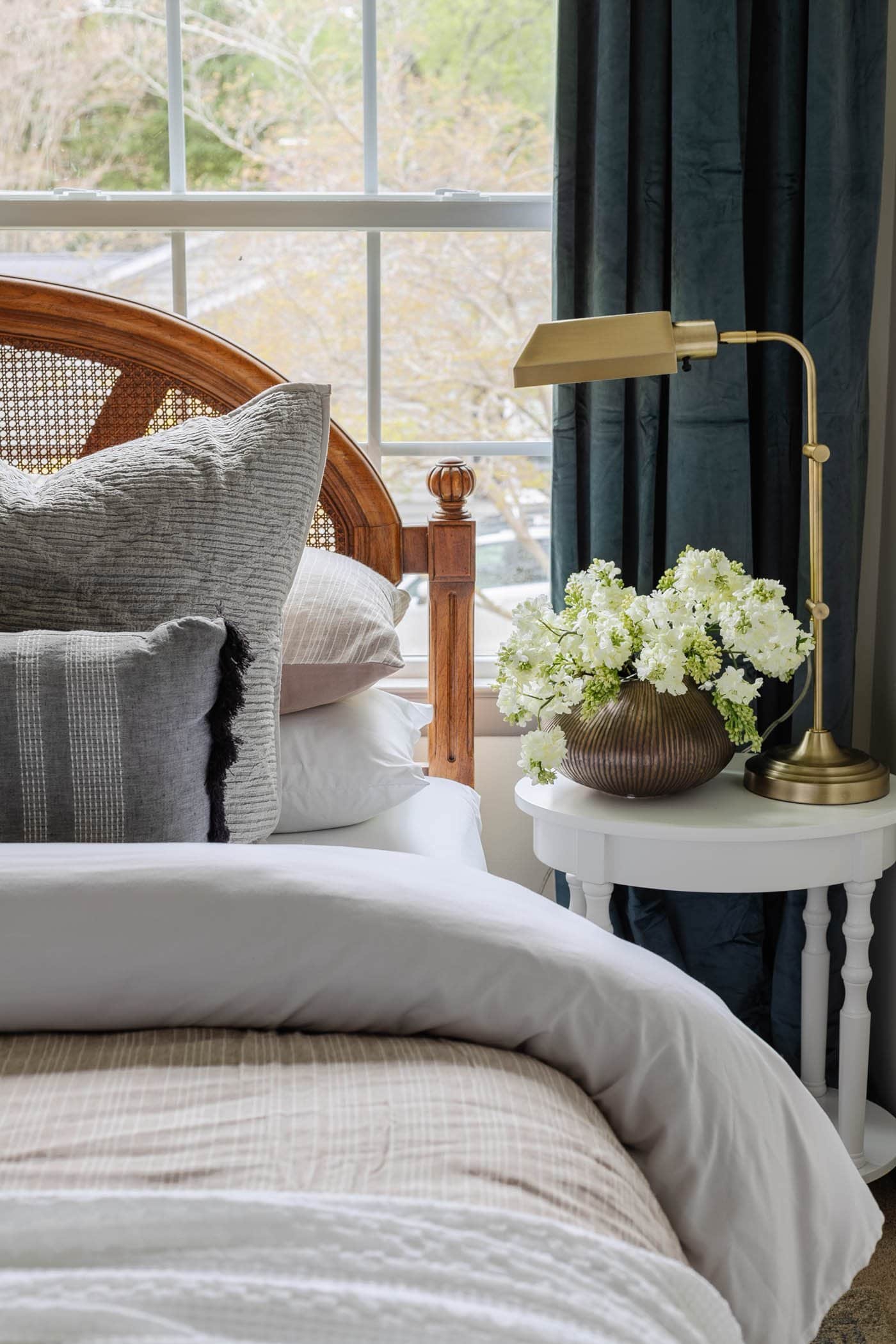 décor de table de chevet avec vase de fleurs et lampe dans une chambre d'amis avec tête de lit en canne