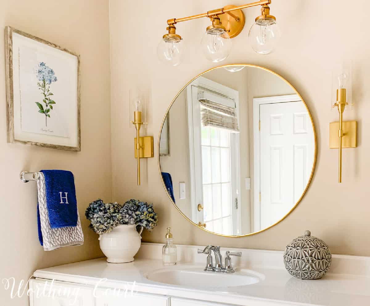 vanité de salle de bain avec miroir rond doré et appliques