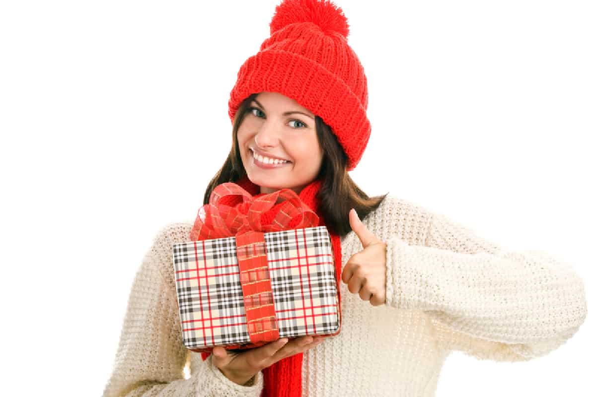 filles dans un pull blanc et un chapeau rouge tenant un cadeau emballé